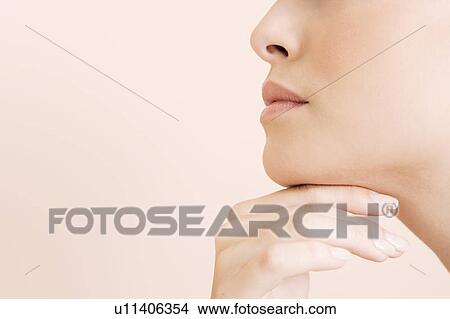 Picture - Detail of young woman's face, hand held under her chin. Fotosearch
