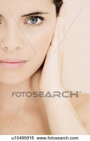 Portrait of young woman holding her hand beside her face View Large Photo Image Stock Photograph - Portrait of young woman holding her hand beside her face. Fotosearch