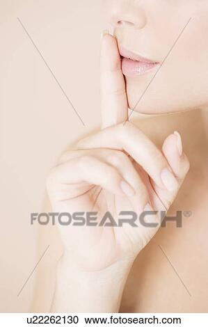 Stock Image - Woman putting her finger to her lips. Fotosearch