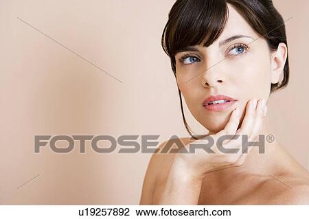 Portrait of a young woman with dark hair in a bun, chin in her hand, thinking View Large Photo Image Stock Image - Portrait of a young woman with dark hair in a bun, chin in her hand, thinking. Fotosearch