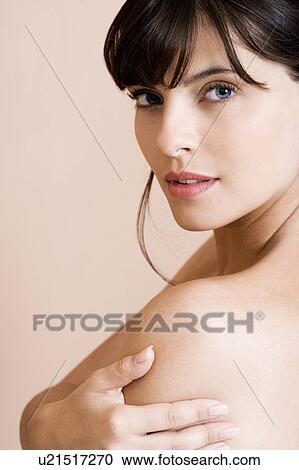 Stock Image - Portrait of young woman with brown hair looking over her shoulder. Fotosearch