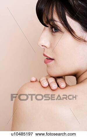 Stock Photo - Portrait of young woman with brown hair looking over her shoulder, profile. Fotosearch