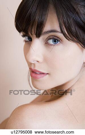 Stock Photo - Portrait of young woman with brown hair looking over her shoulder. Fotosearch