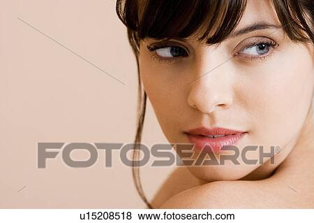 Portrait of young woman with brown hair looking over her shoulder View Large Photo Image Stock Photo - Portrait of young woman with brown hair looking over her shoulder. Fotosearch