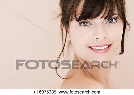 Stock Photography - Portrait of young woman with brown hair looking over her shoulder, smiling. Fotosearch
