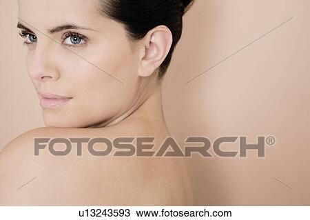 Portrait of a young woman looking over her bare shoulder View Large Photo Image Stock Image - Portrait of a young woman looking over her bare shoulder. Fotosearch