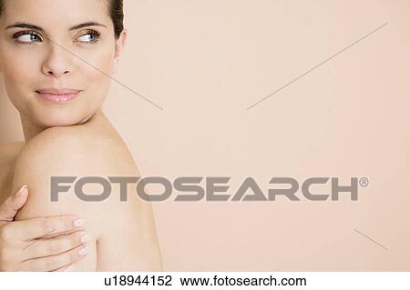 Portrait of a young woman looking over her bare shoulder View Large Photo Image Stock Image - Portrait of a young woman looking over her bare shoulder. Fotosearch