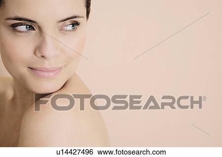 Stock Photograph - Portrait of a young woman looking over her bare shoulder. Fotosearch