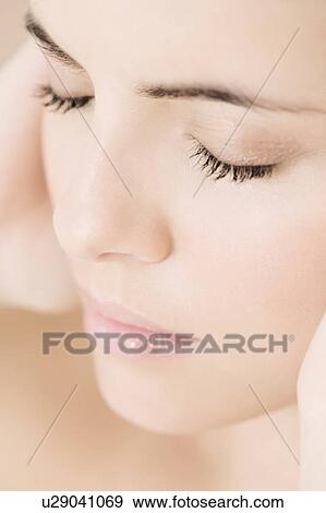 Portrait of young woman holding her hands beside her face View Large Photo Image Stock Photo - Portrait of young woman holding her hands beside her face. Fotosearch