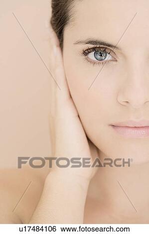 Stock Photograph - Portrait of young woman holding her hand beside her face. Fotosearch