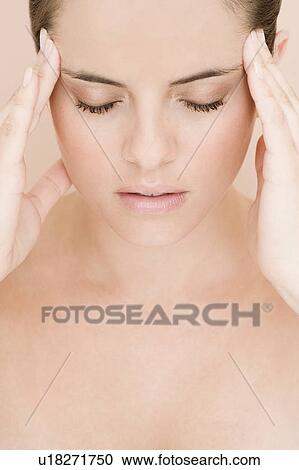 Stock Image - Portrait of young woman with eyes closed and fingers on her temples, concentrating. Fotosearch
