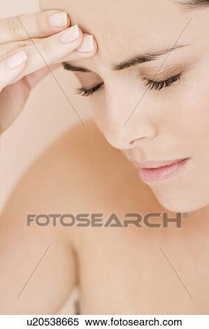 Stock Photography - Portrait of young woman with eyes closed and fingers on her temple, headache. Fotosearch