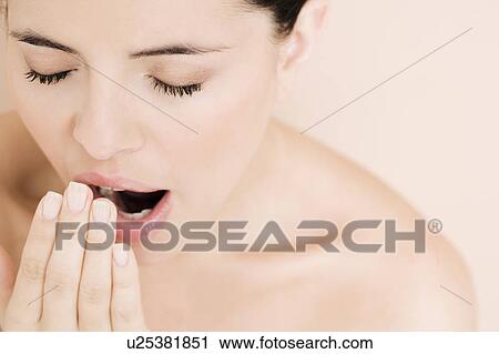 Stock Image - Portrait of young woman yawning. Fotosearch