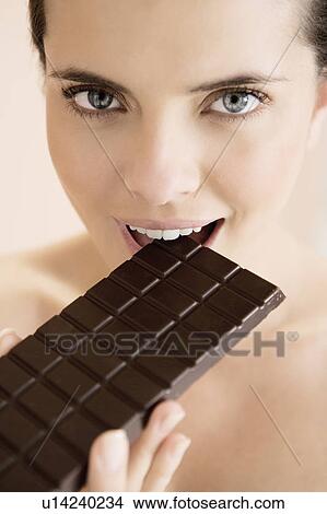 Picture - Woman eating a bar of chocolate. Fotosearch