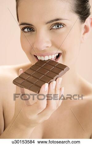 Woman eating a bar of chocolate View Large Photo Image Picture - Woman eating a bar of chocolate. Fotosearch