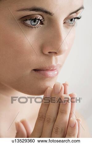 Stock Image - Young woman praying or meditating, hands together. Fotosearch