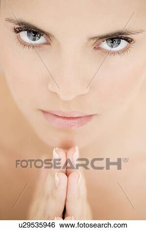 Stock Photograph - Young woman praying or meditating, hands together. Fotosearch