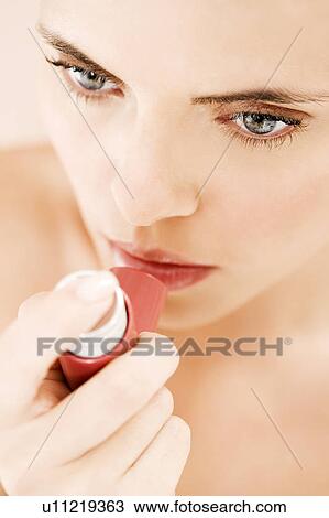 Stock Image - Young woman using an inhaler. Fotosearch
