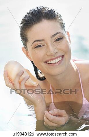 A woman in a pool holding a shell View Large Photo Image Stock Photography - A woman in a pool holding a shell. Fotosearch
