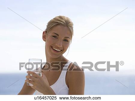 A young woman drinking a glass of water View Large Photo Image Stock Photography - A young woman drinking a glass of water. Fotosearch