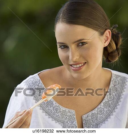 Stock Image - A young woman eating sushi. Fotosearch