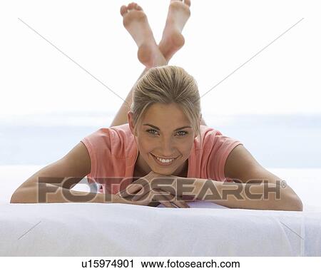 A young woman laying on a bed View Large Photo Image Stock Image - A young woman laying on a bed. Fotosearch