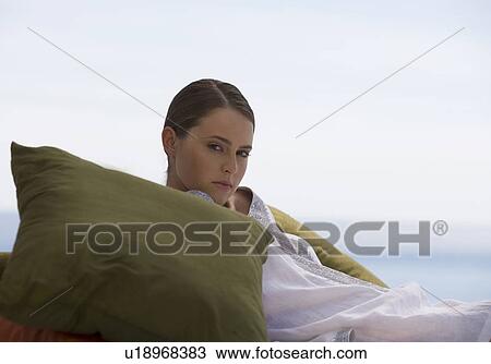 Stock Image - A young woman laying on a bed. Fotosearch