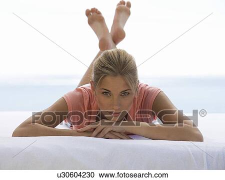 Stock Image - A young woman laying on a bed. Fotosearch