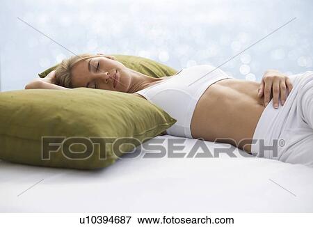 A young woman laying on a bed View Large Photo Image Stock Photo - A young woman laying on a bed. Fotosearch