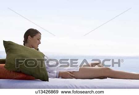Stock Photo - A young woman laying on a bed. Fotosearch