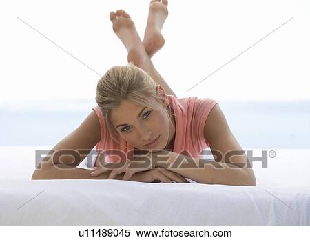 A young woman laying on a bed View Large Photo Image Stock Photography - A young woman laying on a bed. Fotosearch