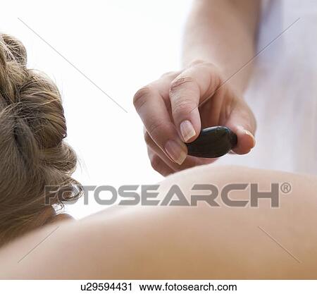 Stock Image - A young woman receiving a hot stone holistic treatment. Fotosearch