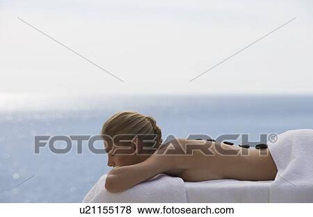 A young woman receiving a hot stone holistic treatment View Large Photo Image Stock Photo - A young woman receiving a hot stone holistic treatment. Fotosearch