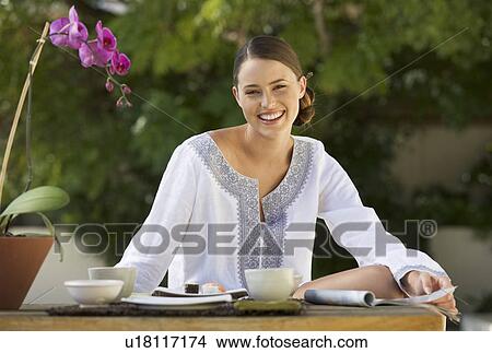 Picture - A young woman sitting at a table. Fotosearch