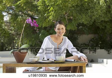 Stock Photography - A young woman sitting at a table. Fotosearch