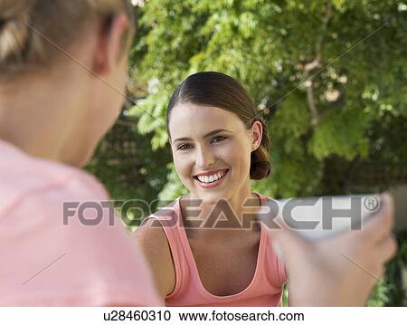 Stock Image - Two young women drinking tea/coffee. Fotosearch