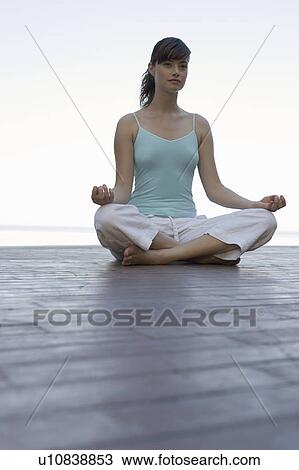 Stock Image - A woman meditating by a pool. Fotosearch