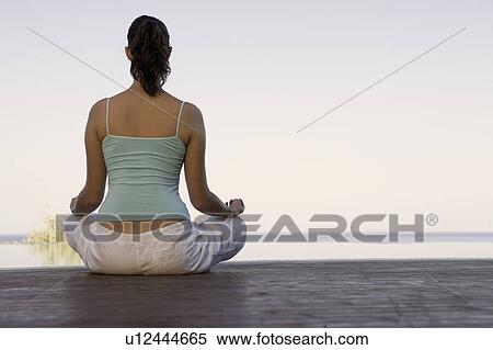 Stock Photography - A woman meditating by a pool. Fotosearch