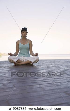 Stock Photography - A woman meditating by a pool. Fotosearch