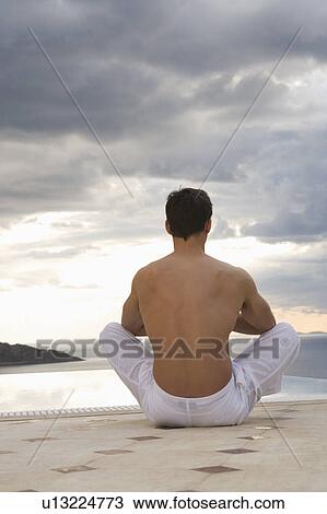 Stock Image - A man meditating by a pool. Fotosearch