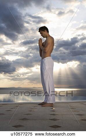 Stock Photography - A man meditating by a pool. Fotosearch
