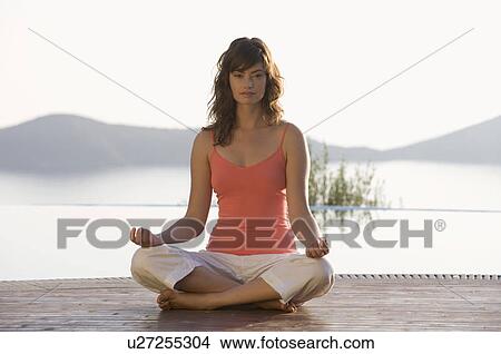 Picture - A woman meditating by a pool. Fotosearch