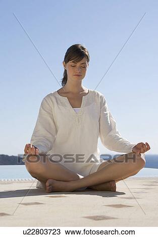 Stock Image - A woman meditating by a pool. Fotosearch