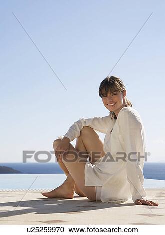 Stock Image - A woman relaxing by a pool. Fotosearch