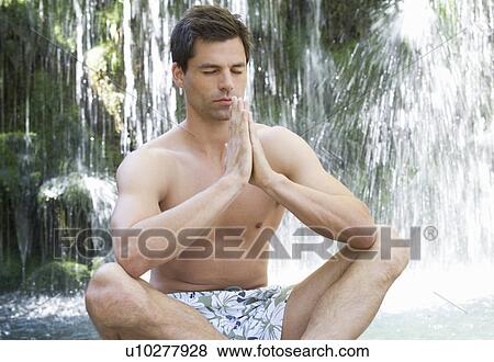 Stock Photo - A man meditating by a waterfall. Fotosearch