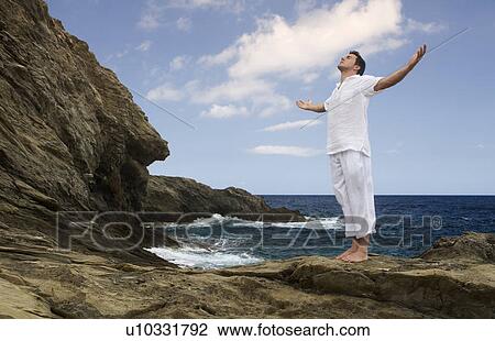 Stock Image - A man meditating by the sea. Fotosearch