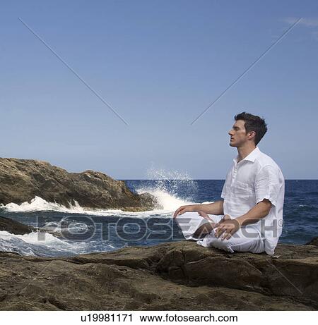 Stock Image - A man meditating by the sea. Fotosearch