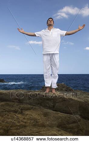 Stock Photo - A man meditating by the sea. Fotosearch