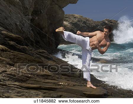 Stock Image - A man practicing Tai Chi by the sea. Fotosearch