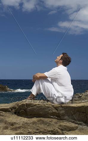Stock Image - A man sitting by the sea. Fotosearch